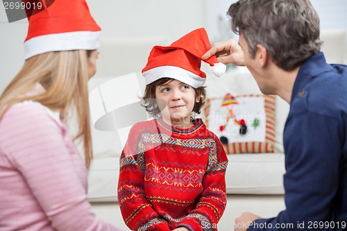 Image of Parents Looking At Son Wearing Santa Hat