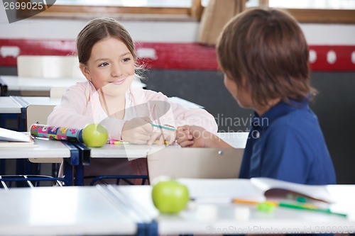 Image of Little Girl Giving Pencil To Boy In Classroom