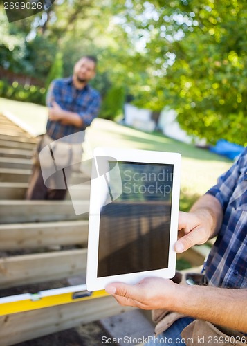 Image of Cropped Image Of Carpenter Holding Digital Tablet At Site