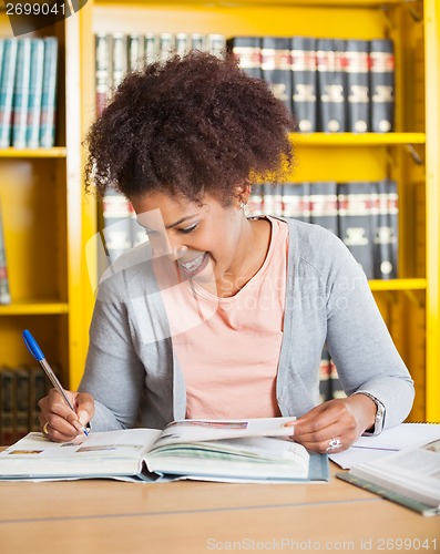 Image of Student Writing In Book At University Library