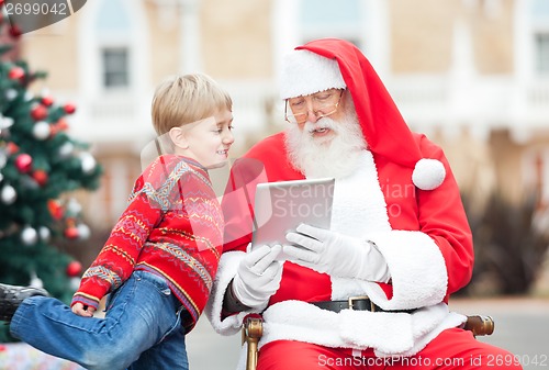 Image of Santa Claus Showing Digital Tablet To Boy