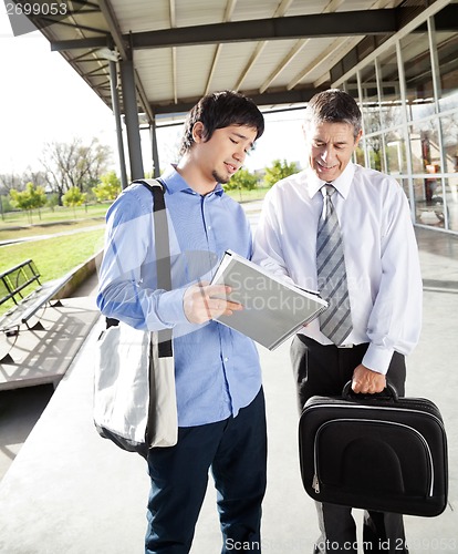 Image of Teacher And Student Discussing Over Book On Campus