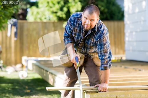 Image of Manual Worker Sawing Wood At Construction Site