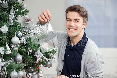 Image of Smiling Man Decorating Christmas Tree