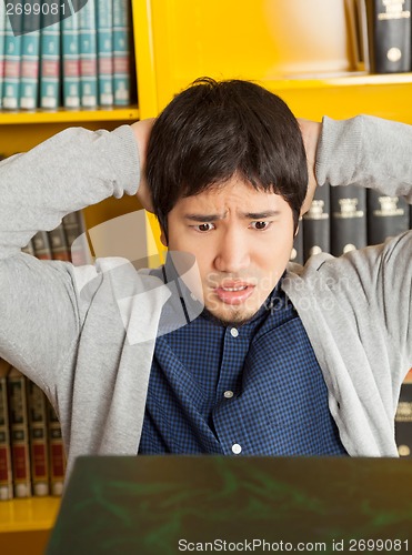 Image of Student With Hands Behind Head Looking At Books In Library