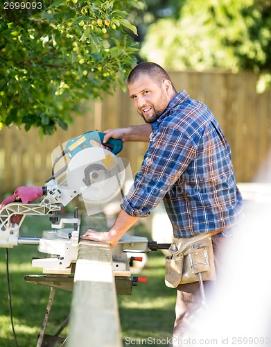 Image of Manual Worker Cutting Wood Using Table Saw At Site