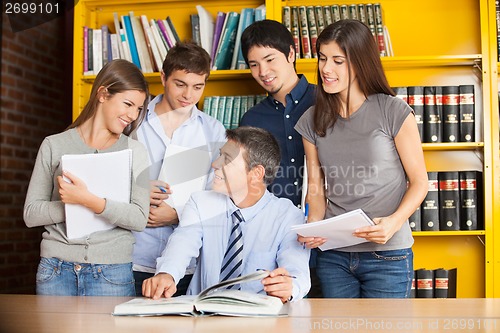 Image of Teacher Pointing At Book While Discussing With Students In Libra