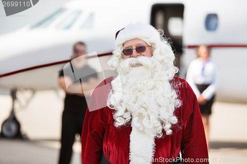 Image of Man In Santa Costume Standing Against Private Jet