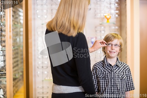 Image of Mother Trying Spectacles On Son At Shop