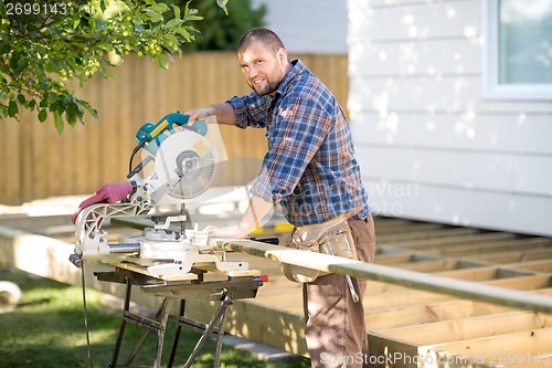 Image of Carpenter Cutting Wood Using Table Saw At Site