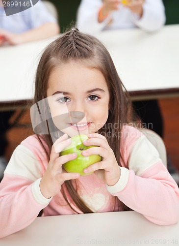 Image of Girl Holding Smith Apple With Classmates In Background