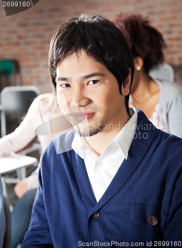 Image of Student Sitting With Classmates In Background At Classroom