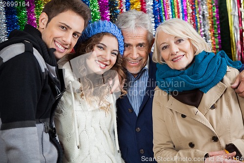 Image of Happy Family Standing Against Tinsels At Store