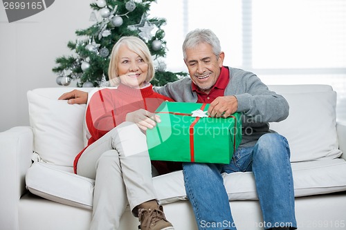 Image of Couple With Christmas Gift Sitting On Sofa