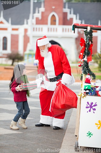 Image of Santa Claus Giving Gift To Girl