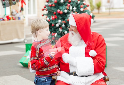 Image of Santa Claus Taking Wish List From Boy