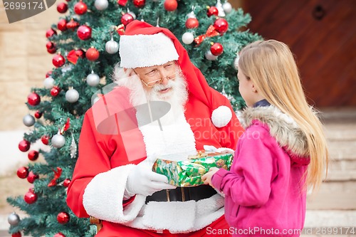 Image of Santa Claus Giving Present To Girl
