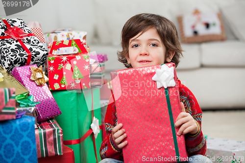 Image of Boy Sitting By Stacked Christmas Presents