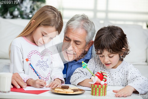 Image of Grandfather Assisting Children In Writing Letters To Santa Claus