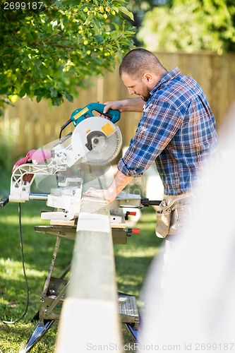 Image of Worker Cutting Wood Using Table Saw At Site