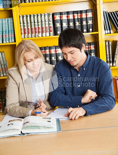 Image of Teacher With Books Explaining Student In University Library