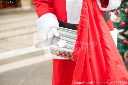 Image of Senior Man Dressed As Santa Claus Putting Gift In Bag