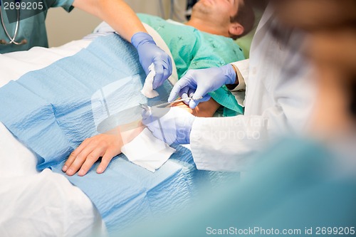 Image of Doctor Stitching Patient's Wound While Nurse Assisting Him