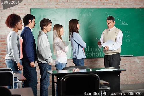 Image of Professor With Exam Results While Students Standing At Desk