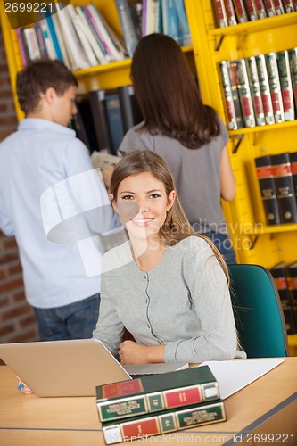 Image of Student With Laptop While Friends Standing In Background At Libr