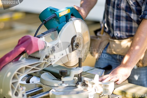 Image of Carpenter Cutting Wooden Plank With Table Saw At Site