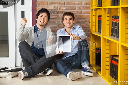 Image of Male Students Showing Digital Tablet While Sitting In Library