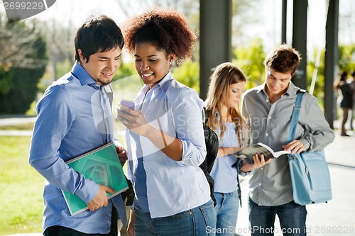 Image of Students Reading Text Message On Mobilephone In Campus