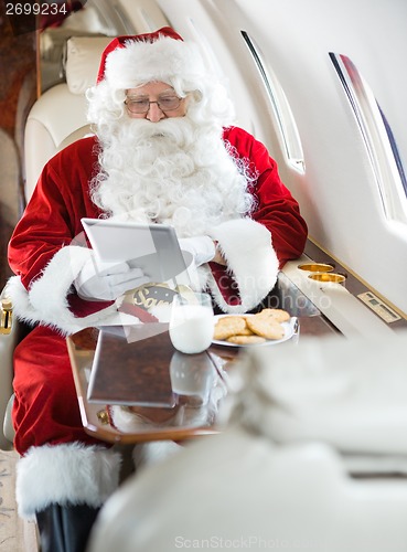 Image of Santa Using Digital Tablet In Private Jet