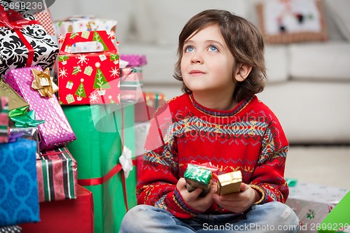Image of Thoughtful Boy Sitting By Christmas Gifts