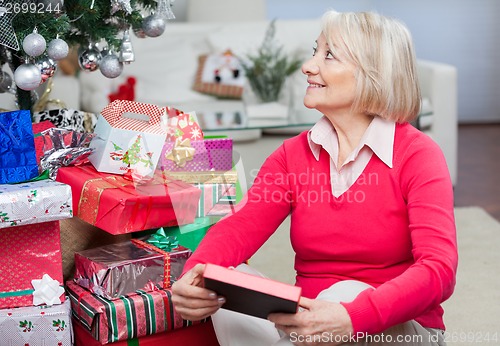 Image of Senior Woman With Christmas Present Looking Away