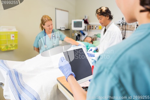 Image of Nurse Holding Digital Tablet While Doctor And Colleague Treating