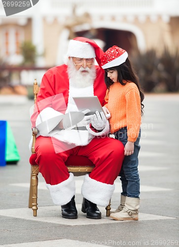 Image of Santa Claus And Girl Using Digital Tablet