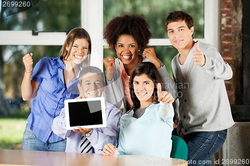 Image of Teacher Holding Digital Table With Students Gesturing In Classro