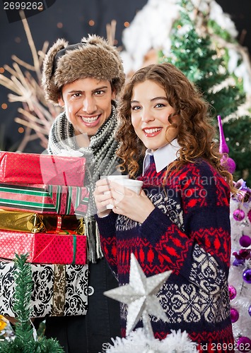 Image of Young Couple With Disposable Cups And Christmas Presents