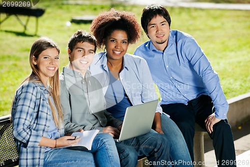 Image of Friends With Laptop And Book Sitting In Campus