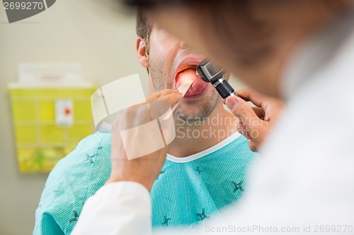 Image of Doctor With Depressor And Otoscope Examining Patient's Tongue