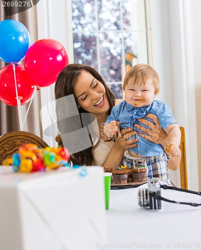 Image of Mother Holding Boy With Messy Hands Covered With Cake Icing