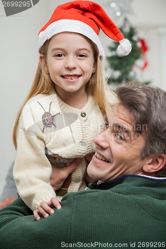 Image of Girl In Santa Hat Being Carried By Father