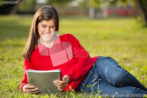 Image of Student Reading Book While Relaxing At College Campus