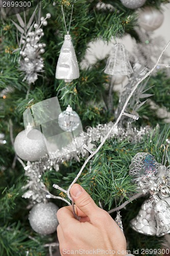 Image of Man Decorating Christmas Tree With Fairy Lights