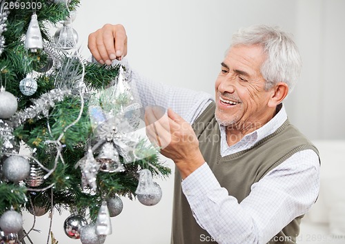 Image of Senior Man Decorating Christmas Tree