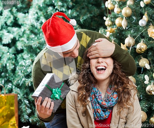 Image of Man In Surprising Woman With Christmas Gift At Store