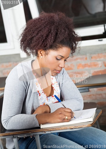 Image of Student Writing Exam At Desk In Classroom