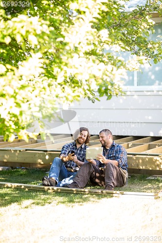 Image of Carpenters With Digital Tablet And Mobilephone Leaning On Wooden