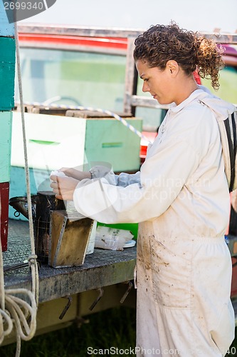 Image of Beekeeper Fueling Smoker For Removing Honey